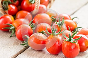 Small red cherry tomatoes spill out of a wicker basket.