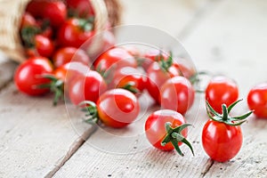 Small red cherry tomatoes spill out of a wicker basket