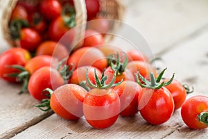 Small red cherry tomatoes spill out of a wicker basket.