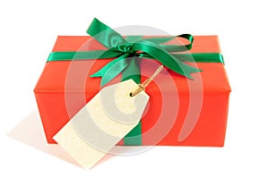 Small red christmas or birthday gift with green ribbon bow, gift tag or label, isolated on white background