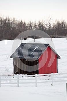 Small, red cottage in the middle of a snow-covered meadow