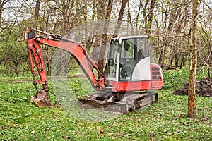 A small red excavator in the woods