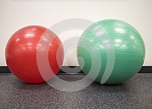 Small red exercise ball beside a medium size swiss ball in the gym