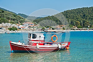 Small red fishing boat at Panormos bay in front of Panormos beach, island of Skopelos