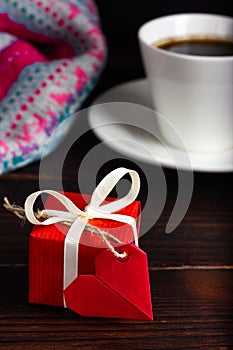 Small red gift with a heart-shaped note. Gift for February 14th. A gift to your loved one. A surprise for a loved one.