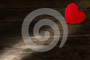 Small red heart on wooden desk in light