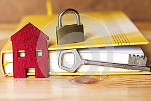 small red house with key, padlock and book, sell house business concept.