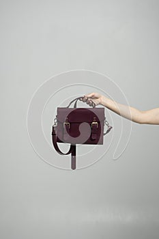 Small red leather bag in a woman& x27;s hand on a white background. Shoulder handbag. Style, retro, fashion, vintage and