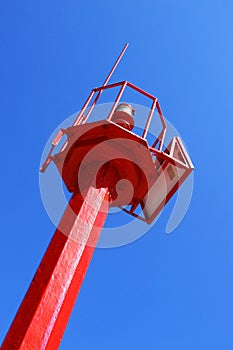 Small red light house on blue background at sunny day