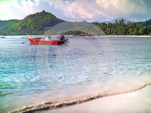 Small red motorboat anchored off a Seychelles beach on a sunny y
