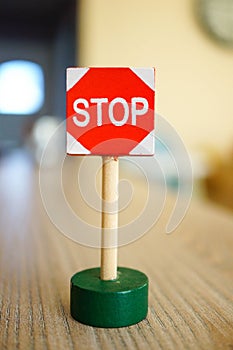 Small red stop sign on a wooden table under the lights with a blurry background