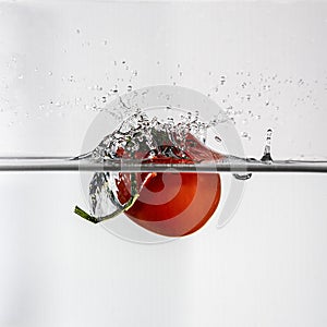 small red tomato drop in water with a splash