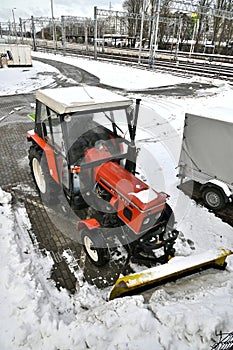 Small red tractor with snow plow for street cleaning