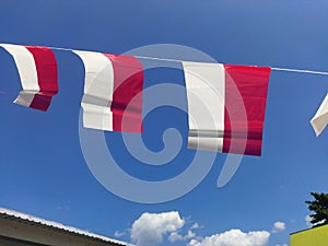 Small red and white flags against a blue sky background. Indonesian independence day celebration.