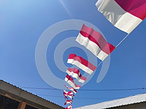 Small red and white flags against a blue sky background. Indonesian independence day celebration.