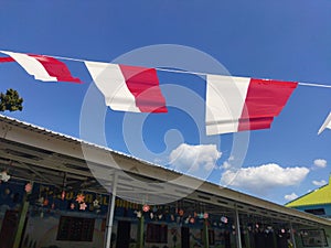 Small red and white flags against a blue sky background. Indonesian independence day celebration.