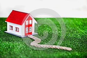 Small red and white houses on green grass.House on green grass. Give the route as a coin