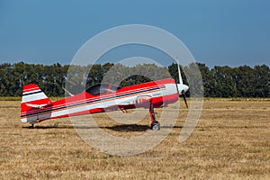 Small red and white private plane with propeller stands at the airport