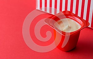 Small red yogurt cup with fruit yoghurt isolated on fun red background