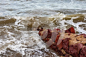 Small reddish brown irregular stone wall on beach