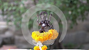 Small replica of Ganesh with iron color is worshiped with a glowing yellow marigold.