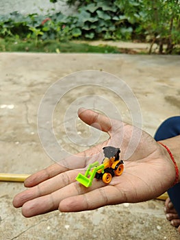 A small replica of JCB trailer on the hand of a north Indian man in natural background