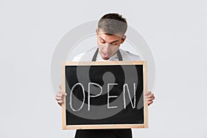 Small retail business owners, cafe and restaurant employees concept. Amused happy salesman, waiter inform about opening