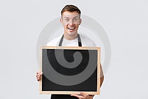Small retail business owners, cafe and restaurant employees concept. Happy smiling handsome salesman showing blank board