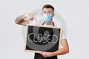 Small retail business owners, covid-19 and social distancing concept. Disappointed and sad salesman in medical mask