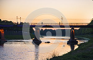 A small river in the city and a bridge over the river. Cityscape with old houses and cloudy skies.