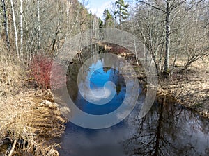 A small river in early spring, blue skies and reflections in the water