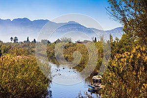 Small river with fishing boats, vegetation and ducks