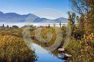 Small river with fishing boats, vegetation and ducks