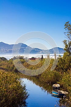 Small river with fishing boats, vegetation and ducks