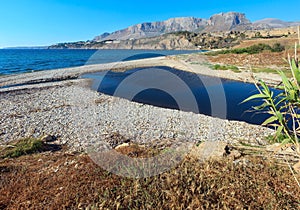 Small river flows into the sea on pebble beach