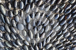 Small river rocks set in concrete in a abstract pattern, as graphic background