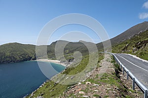 Small road on a hill leading to a sandy Keem beach in Achill island, Ireland. Warm sunny day. Clear blue sky. Irish landscape.