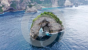 Small Rock Arch Island in the Sea. Nusa Penida, Indonesia. 4K Aerial View