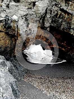 A small rock arch receives the waves of the sea