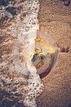 small rock getting hit by wave at beach