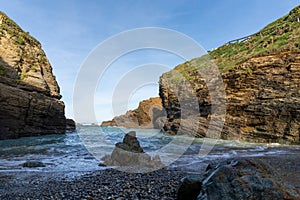 Small rock and sand beach in a sheltered cove with cliffs on the side photo