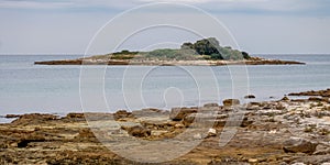 Small rocky island with rocky shore in foreground