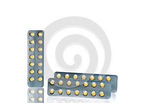 Small round light yellow enteric-coated tablet pills in blister pack isolated on white background with copy space. Medicine for tr photo