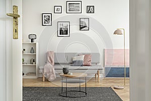 Small round wooden coffee table in front of trendy sofa in elegant interior