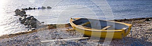 Small row boat laying on a pebble beach