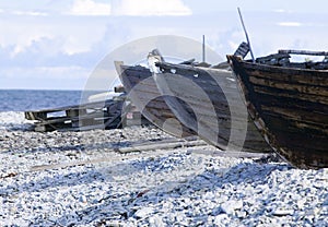 Small row boats laying on a pebble beach