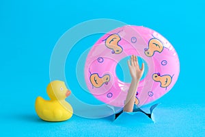 Small rubber duck and doll hand from the water with inflatable pool float minimalistic abstract.