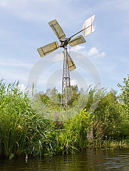 Small and rusted old metal windmill at the waterside