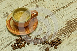 A small rustic coffee mug stands on an old wooden