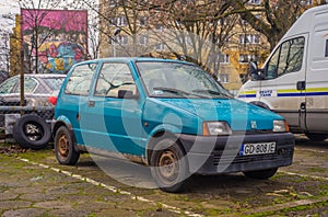 Small rusty old blue car Fiat Cinquecento parked
